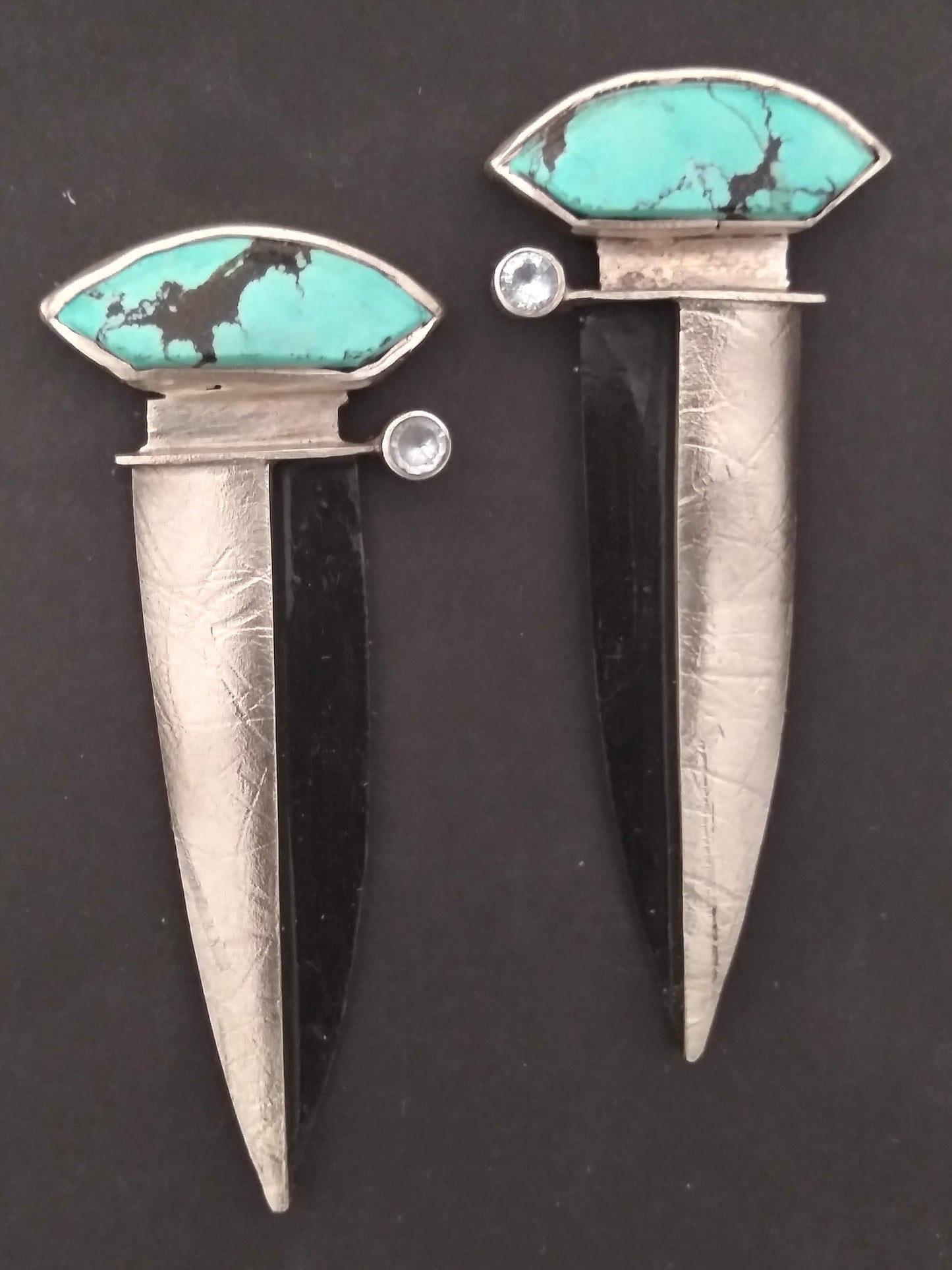 A pair of silver earrings with turquoise and a clear stone inlay