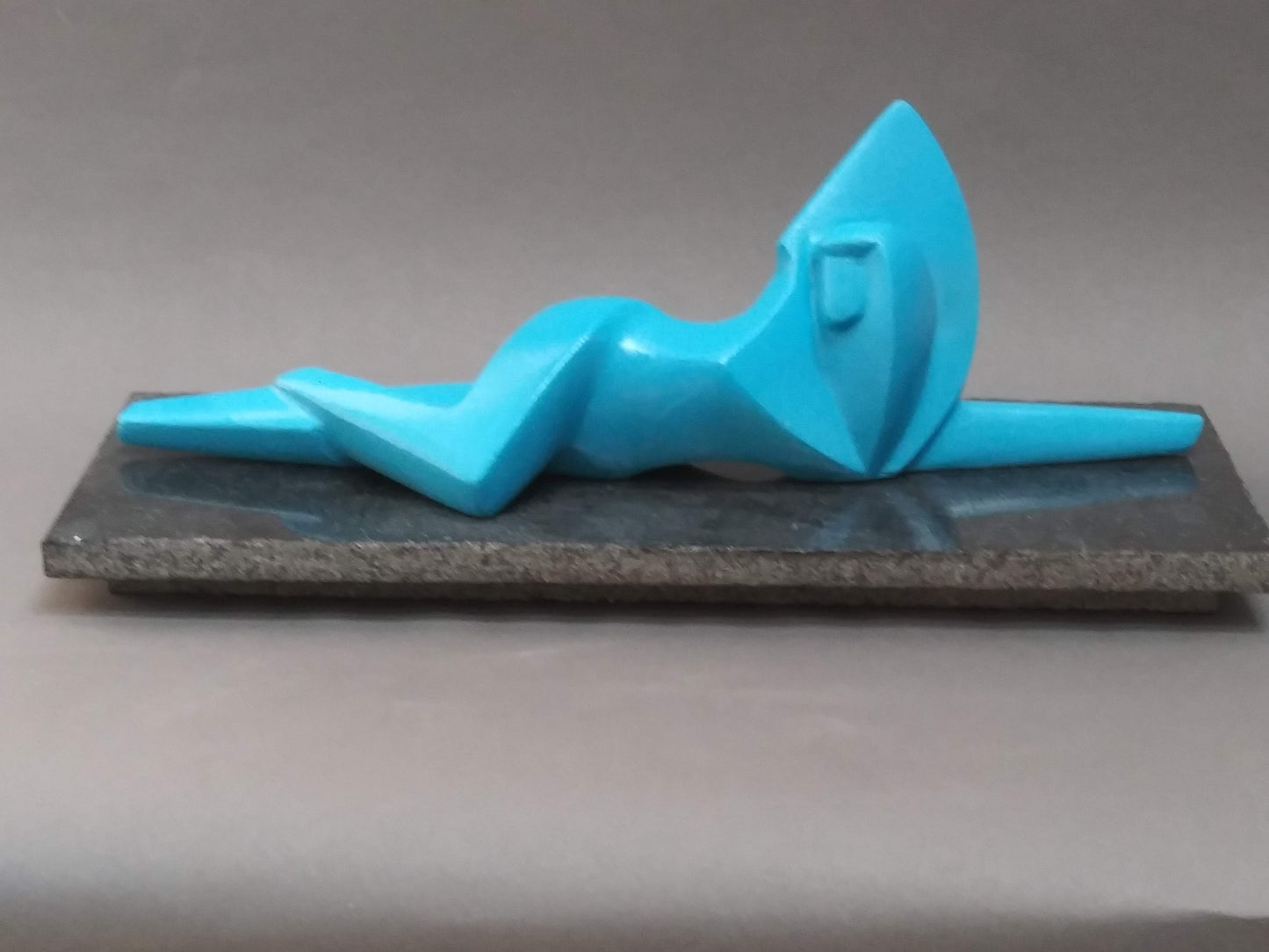 A bright blue, abstract sculpture of a reclining figure by Reno Carollo, titled 'Reclining Figure 1969-70'.